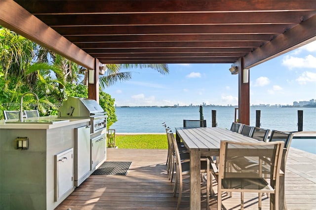 view of dock featuring an outdoor kitchen, a deck with water view, a pergola, and sink