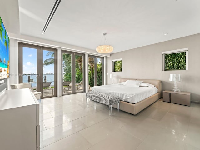 bedroom featuring multiple windows, a water view, light tile patterned flooring, and access to exterior