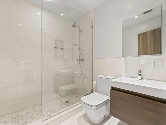 bathroom with tiled shower, vanity, toilet, and tile walls