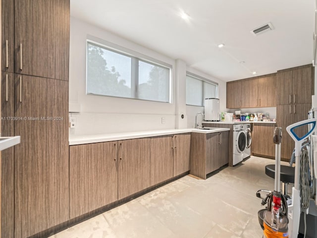 kitchen featuring light tile patterned floors, washing machine and dryer, and sink