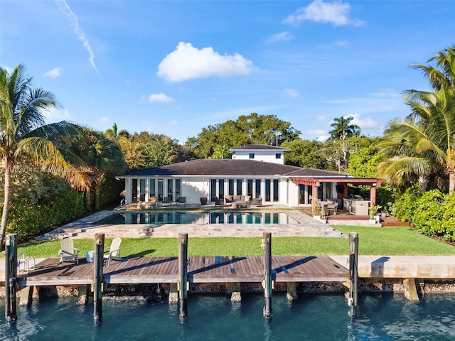 rear view of house with a lawn, a swimming pool, a water view, and a patio