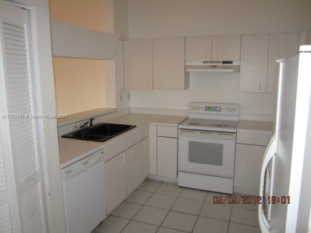 kitchen with sink, white cabinets, white appliances, and light tile patterned floors