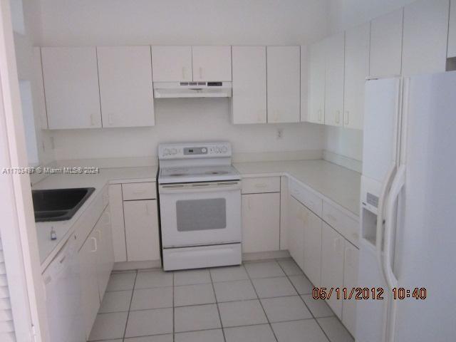 kitchen featuring white cabinets, light tile patterned flooring, white appliances, and sink