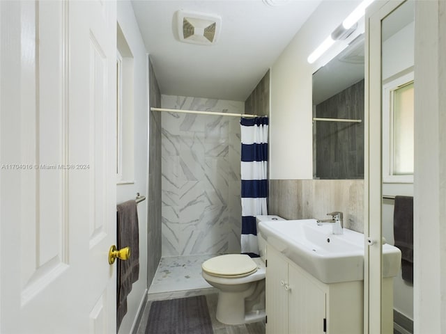 bathroom featuring vanity, toilet, walk in shower, and tile walls