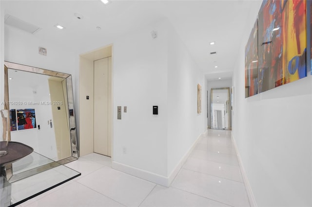 hallway with tile patterned floors, baseboards, and elevator