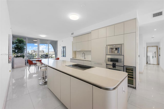 kitchen with visible vents, a wall of windows, beverage cooler, oven, and black electric stovetop