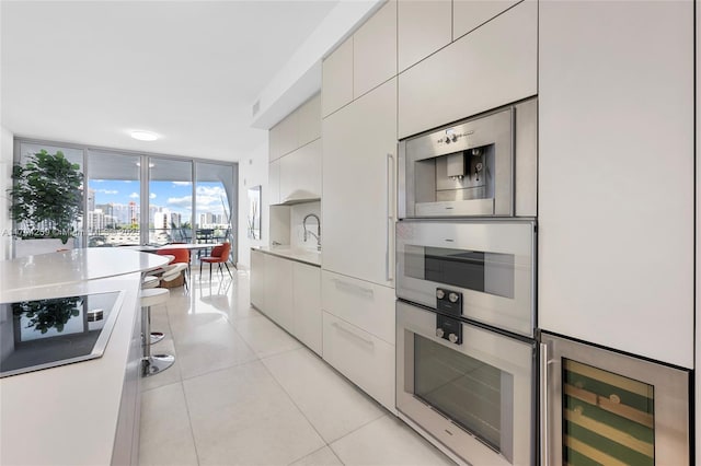 kitchen featuring light countertops, beverage cooler, black electric cooktop, light tile patterned floors, and modern cabinets