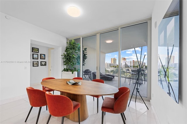 dining space with light tile patterned floors, a view of city, baseboards, and expansive windows