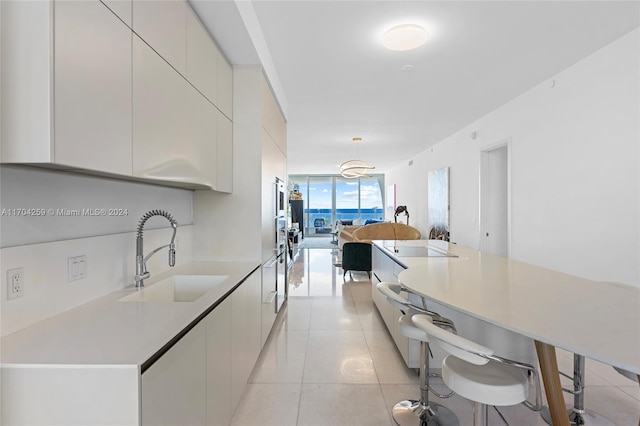 kitchen featuring pendant lighting, a breakfast bar, floor to ceiling windows, sink, and light tile patterned flooring