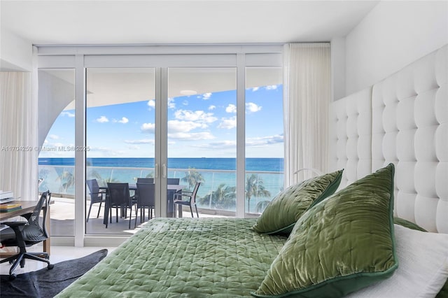 bedroom featuring access to outside, a water view, and expansive windows