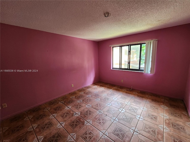 tiled spare room with a textured ceiling