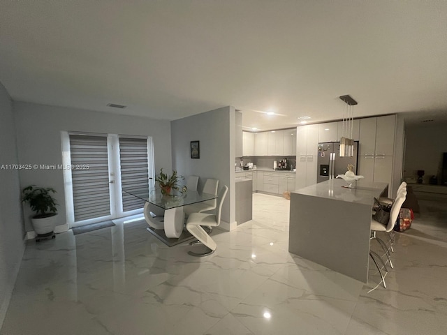 kitchen featuring white cabinetry, marble finish floor, light countertops, stainless steel fridge with ice dispenser, and pendant lighting