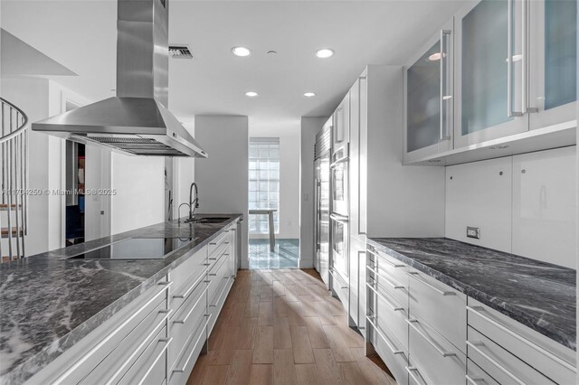 kitchen with white cabinetry, island exhaust hood, black electric stovetop, and sink