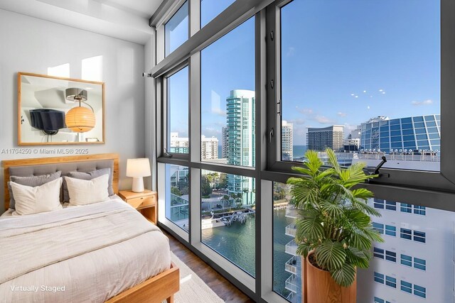 bedroom with a water view, dark wood-type flooring, and access to outside