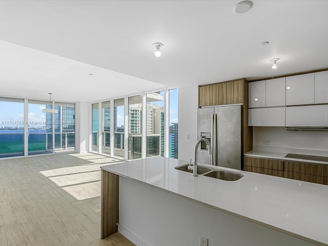 kitchen with white cabinets, stainless steel refrigerator with ice dispenser, pendant lighting, and a healthy amount of sunlight