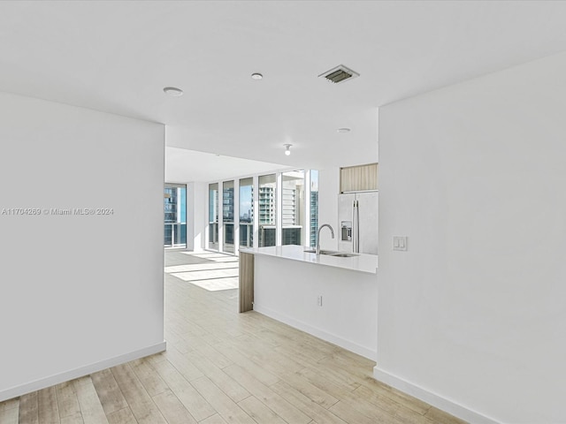 kitchen with light hardwood / wood-style flooring, white fridge with ice dispenser, and sink