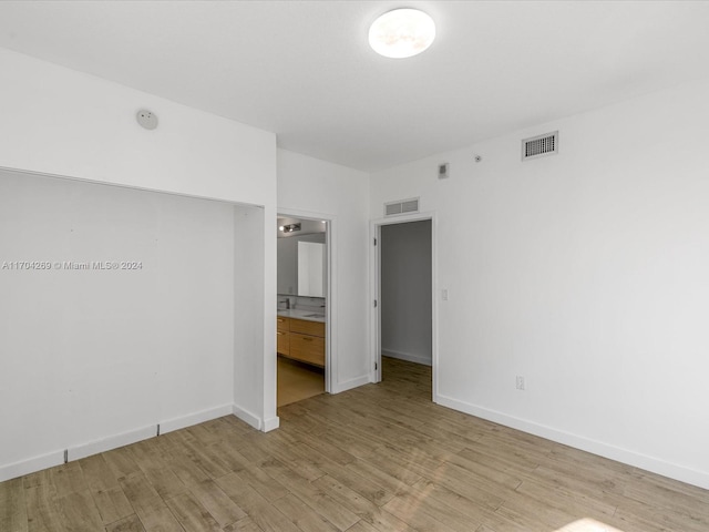 unfurnished bedroom with connected bathroom and light hardwood / wood-style flooring