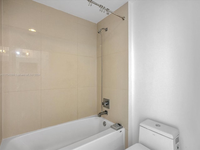 bathroom featuring toilet and tiled shower / bath