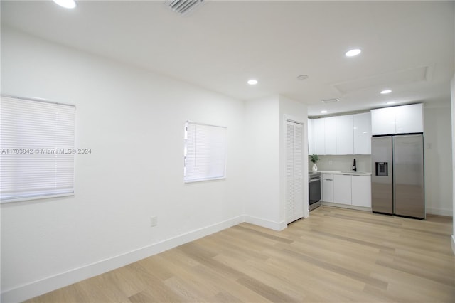 kitchen with white cabinets, light wood-type flooring, stainless steel appliances, and sink