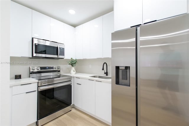 kitchen featuring white cabinets, stainless steel appliances, light hardwood / wood-style flooring, and sink