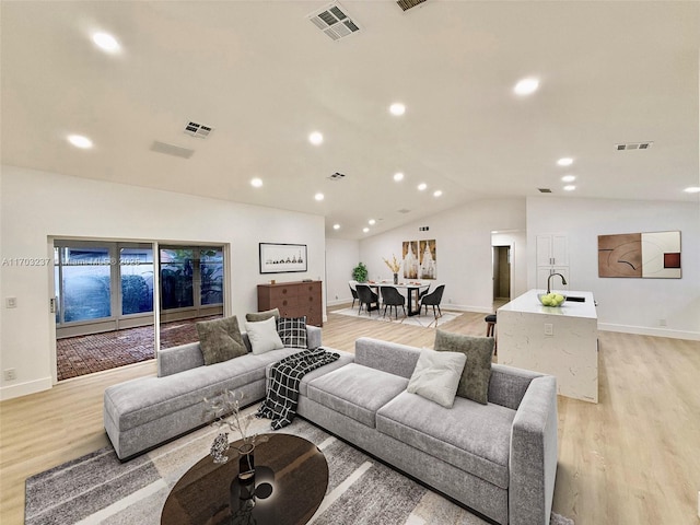 living room featuring sink, light wood-type flooring, and lofted ceiling