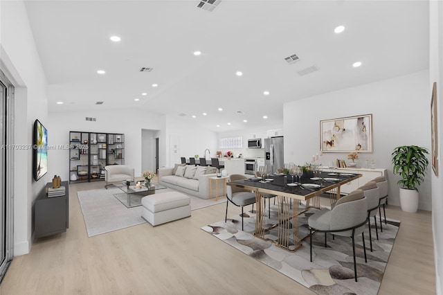 dining area with lofted ceiling and light wood-type flooring