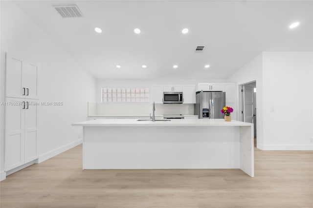 kitchen with stainless steel appliances, white cabinets, sink, and a kitchen island with sink