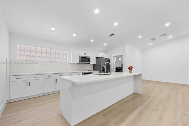 kitchen with sink, white cabinets, light wood-type flooring, an island with sink, and appliances with stainless steel finishes