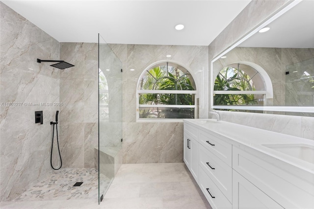 bathroom with tile walls, a tile shower, and vanity