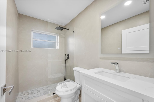 bathroom with toilet, a tile shower, and vanity