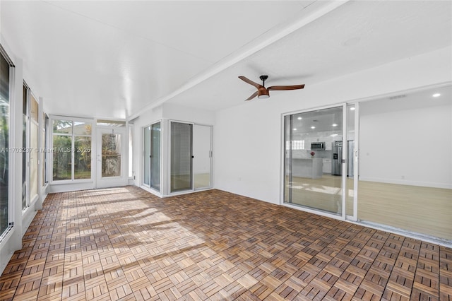 unfurnished sunroom featuring ceiling fan