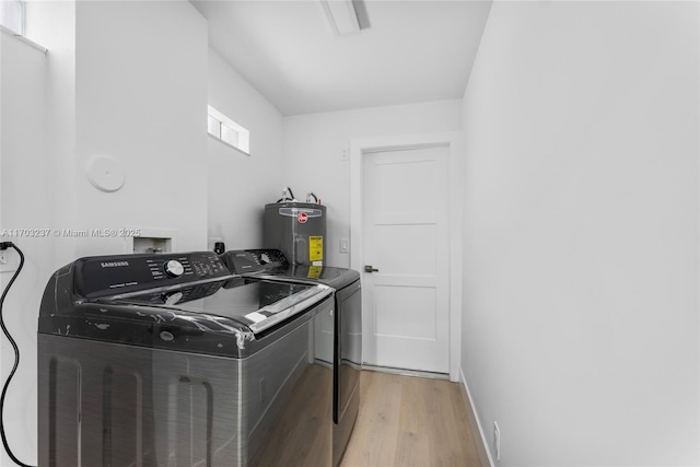 laundry room featuring water heater, light hardwood / wood-style floors, and washer and clothes dryer