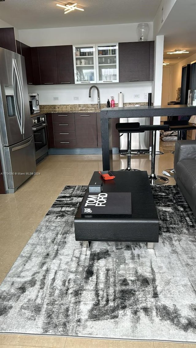 41 SE 5th St Unit 2011, Miami, FL 33131 - kitchen featuring stainless steel refrigerator with ice dispenser, wall oven, dark stone counters, dark brown cabinetry, and a sink