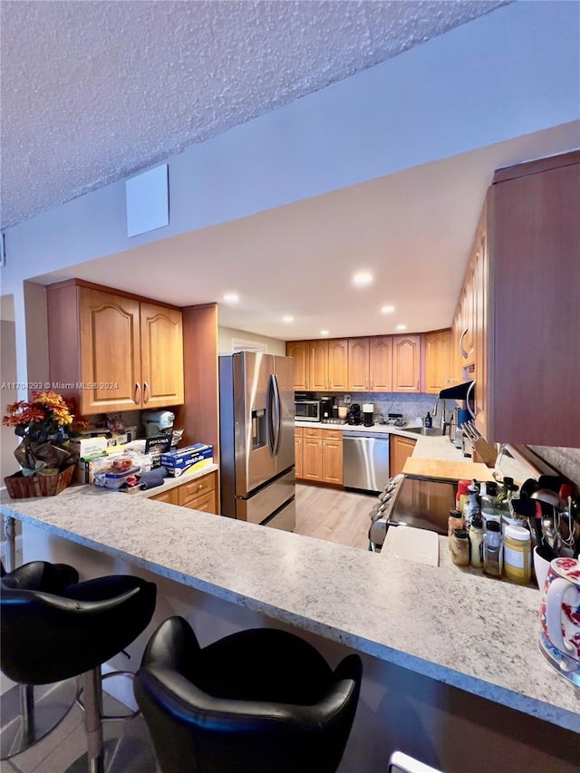 kitchen with kitchen peninsula, a breakfast bar, and stainless steel appliances