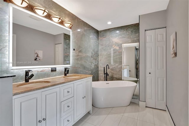 bathroom featuring vanity, a bath, tile patterned floors, tile walls, and tasteful backsplash