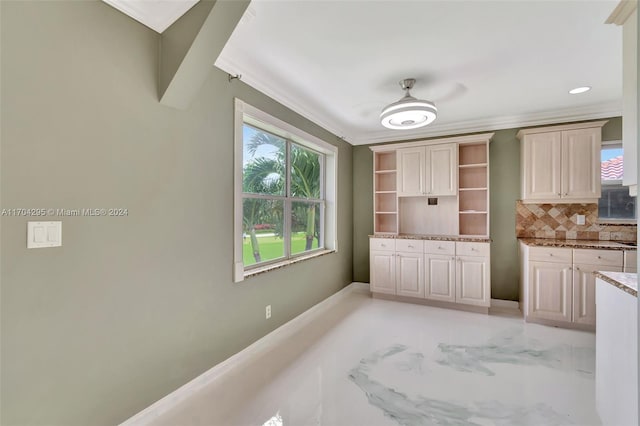 kitchen featuring decorative backsplash, light stone counters, and crown molding