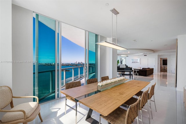 dining room featuring light tile patterned floors, a water view, and floor to ceiling windows