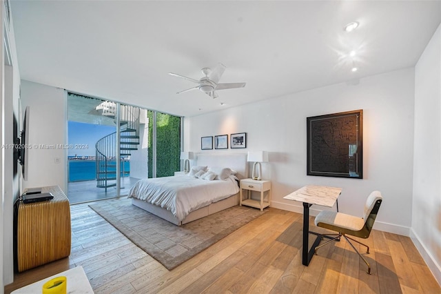 bedroom featuring access to exterior, expansive windows, light hardwood / wood-style flooring, and ceiling fan