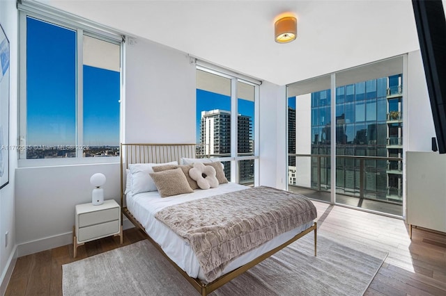 bedroom featuring access to outside, floor to ceiling windows, and hardwood / wood-style flooring