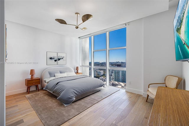 bedroom featuring access to outside, floor to ceiling windows, ceiling fan, and light wood-type flooring