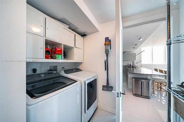 laundry area with cabinets, washing machine and dryer, and light tile patterned floors