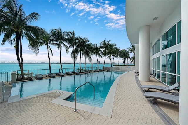 view of pool with a patio area and a water view