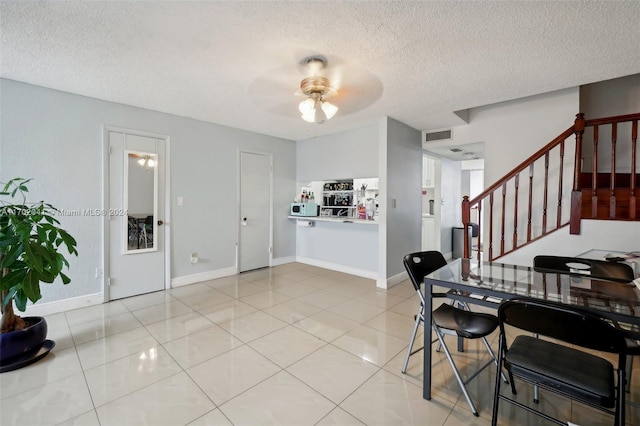 dining room with a textured ceiling, ceiling fan, and light tile patterned flooring