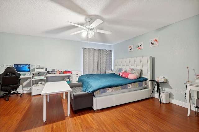 bedroom with ceiling fan, wood-type flooring, and a textured ceiling