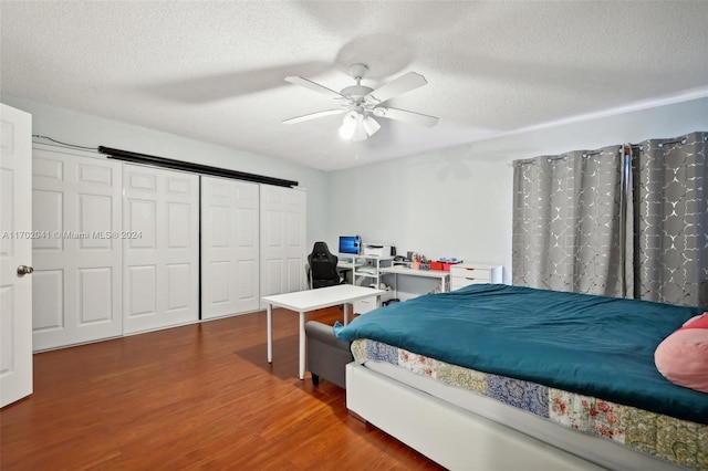 bedroom with ceiling fan, dark hardwood / wood-style floors, a textured ceiling, and a closet