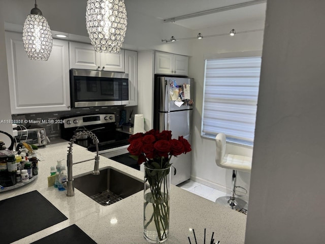 kitchen featuring white cabinets, sink, decorative backsplash, a notable chandelier, and stainless steel appliances