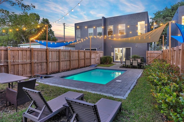 pool at dusk featuring a patio