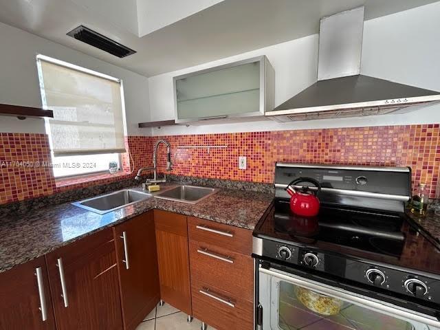 kitchen with tasteful backsplash, stainless steel range, wall chimney exhaust hood, and sink