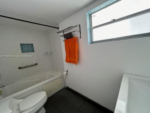 bathroom featuring tile patterned floors, tiled shower / bath combo, and toilet