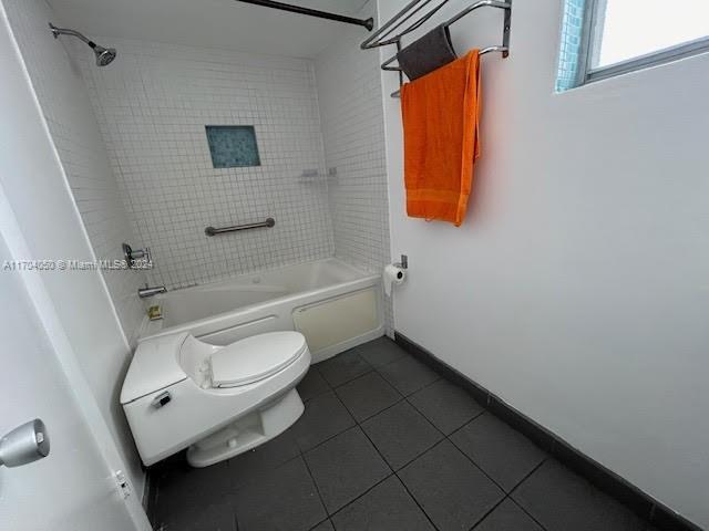 bathroom with toilet, tiled shower / bath combo, and tile patterned floors